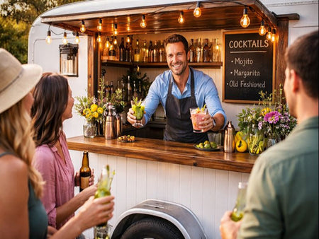 Man serving drinks at a mobile bar with customers enjoying cocktails outdoors.